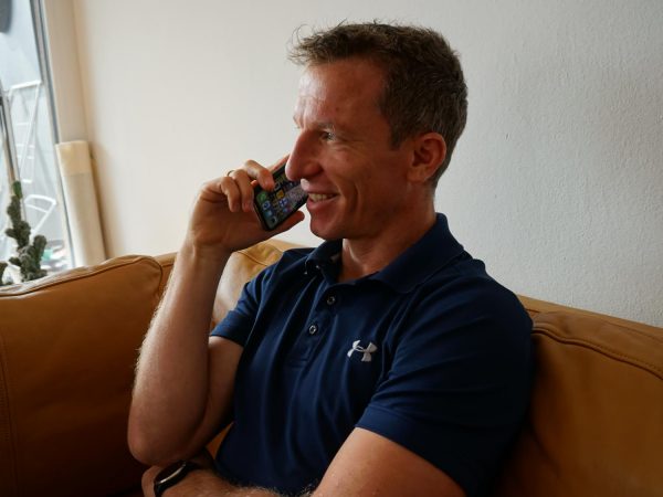 falko krismayr network marketing expert sitting on a couch talking on a cell phone.