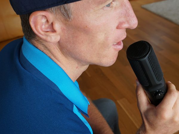 falko krismayr network marketing expert in a hat holding a microphone.