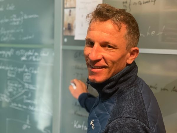 falko krismayr network marketing expert standing in front of a blackboard with writing on it.